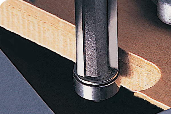 Trimming veneer flush with the edge of a workpiece using a trimming and profiling cutter