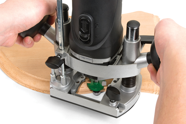 A DIYer using an ovolo router cutter to produce a decorative edge on a wooden workpiece