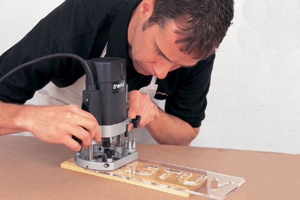 Engraving a piece of wood using a template, a hand-held router and a radius engraving router cutter